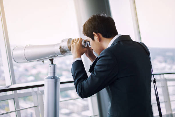 empresario asiático con los binoculares en la parte superior del edificio - grave nature usa city life fotografías e imágenes de stock