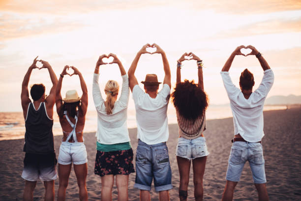 istock Friends standing in sand showin hearts 672450340