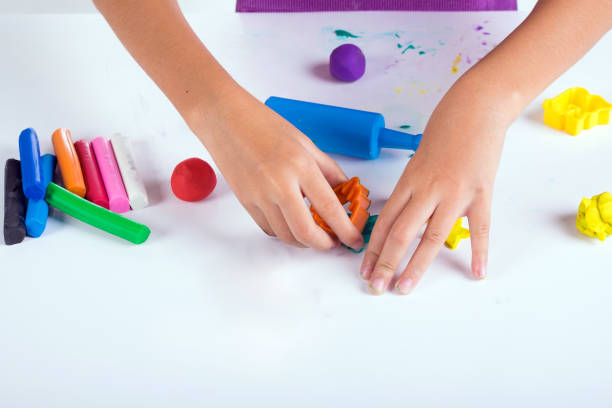 istock Little hand of kid learn to play coloful dough on white table 672463234
