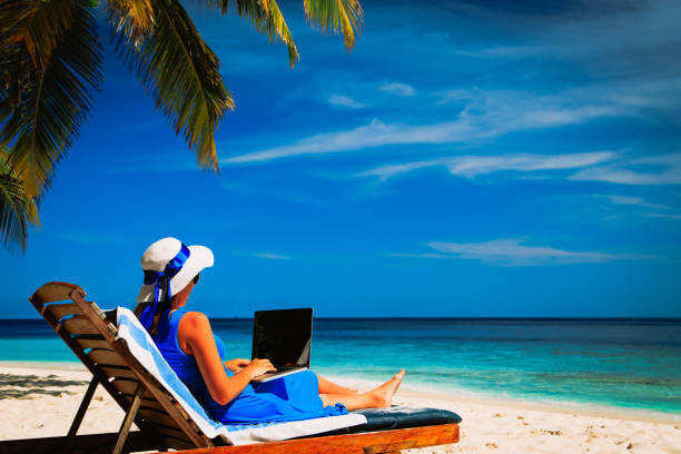 istock young woman with laptop on tropical beach 672470108