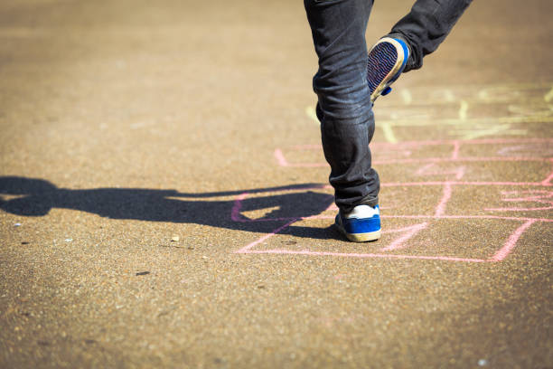 istock little boy playing hopscotch on playground 672471586