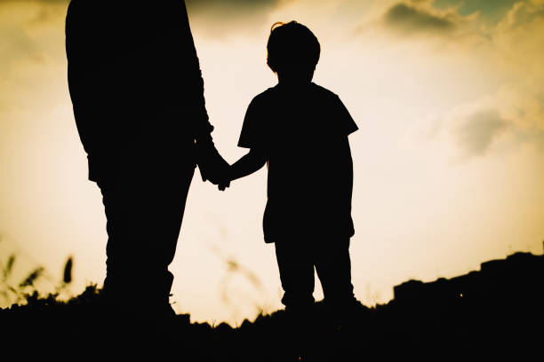 istock silhouette of father and son holding hands at sunset 672471610
