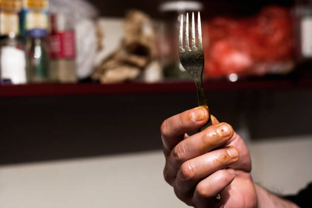 Close-up of oily hand holding fork in a kitchen