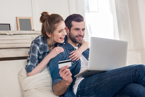 Young couple making online payment using credit card and laptop