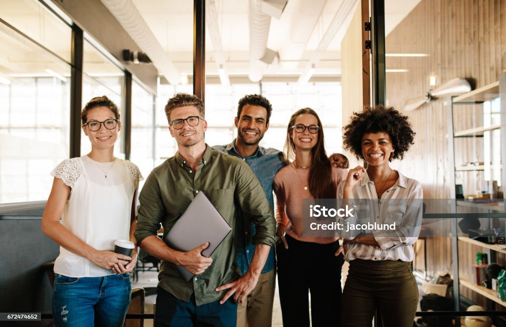 Portrait of successful creative business team Portrait of successful creative business team looking at camera and smiling. Diverse business people standing together at startup. Group Of People Stock Photo