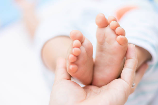 istock mother hands holding tiny baby feet 672475176