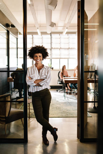 bem sucedida jovem encostado à porta do escritório - door office business women - fotografias e filmes do acervo