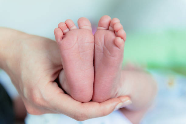 istock Cute baby feet, held by careful mother 672475556