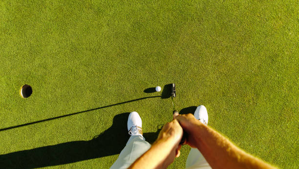 golf player at the putting green hitting ball into a hole - putting green imagens e fotografias de stock