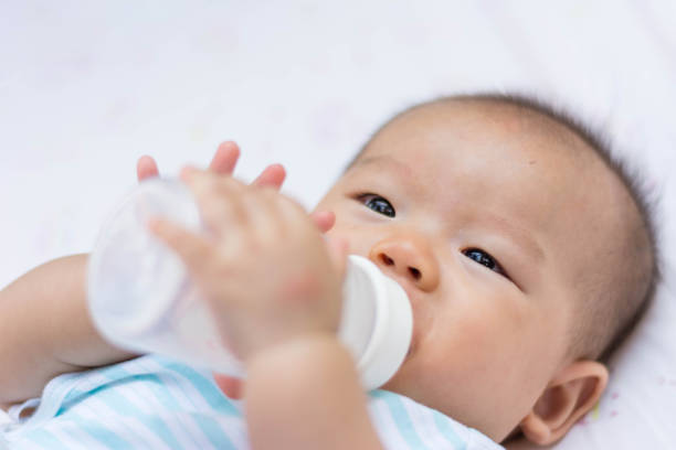 istock Smiling Asian baby infant enjoy drinking water from bottle 672482678