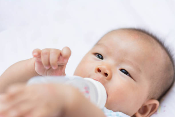 istock Smiling Asian baby infant enjoy drinking water from bottle 672483258