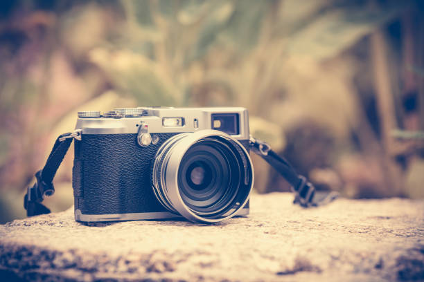 istock Vintage-style digital camera on boulder over blurred nature background. Outdoor. 672495400