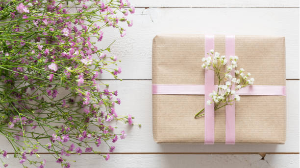 istock Mother's day, white wooden table with flowers and a present 672496312