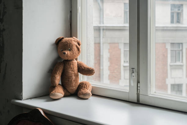 istock Lonely vintage teddy bear on the  window 672497590