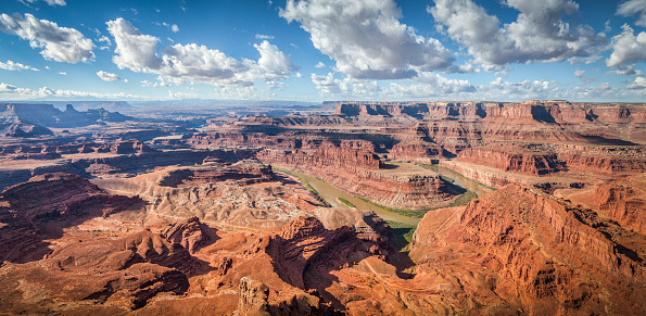 Aerial panoramic view of scenic Dead Horse Point State Park with famous Colorado river flowing on a beautiful sunny day with blue sky and dramatic clouds in summer, Utah, American Southwest, USA