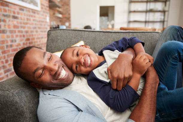 istock Father And Son Cuddling On Sofa Together 672516958