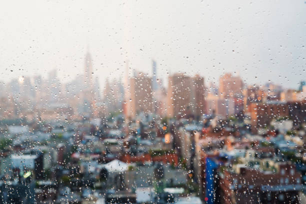 New-York skyline rapidly changing from sunny to rainy weather. This is a view up Manhattan from Tribeca. Empire State building visible in background. Horizontal outdoors shot through window with raindrops and copy space. This was taken in New-York, USA.