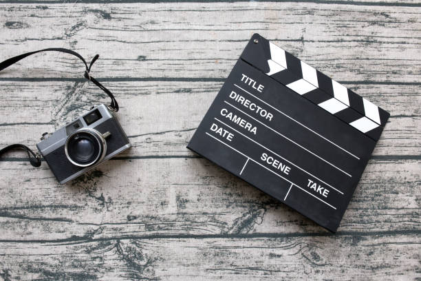istock Vintage camera and slate or clapper board on wood print tablecloth background. 672528194