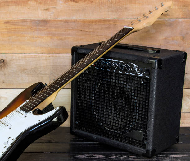 istock Electric guitar with guitar amplifier on wooden background 672531480