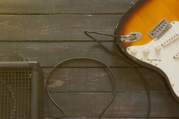 istock Electric guitar with black amplifier connected by cable on wooden floor 672531496