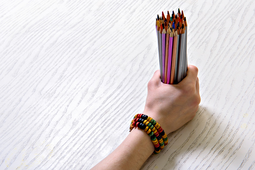 Close up of female hand clenching amount of crayons. Top view. Copy space
