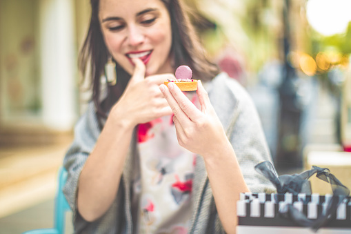 Positive energy woman with short hair, winking by showing the candy ring in her hand.