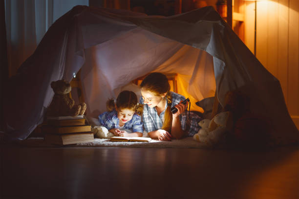 istock mother and child daughter with a book and a flashlight before going to bed 672566816