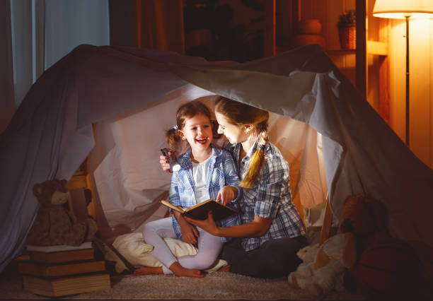 istock mother and child daughter with a book and a flashlight before going to bed 672566886