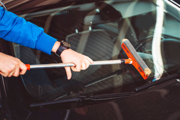 istock Worker Washing Windshield Of Car At Service Station 672574826
