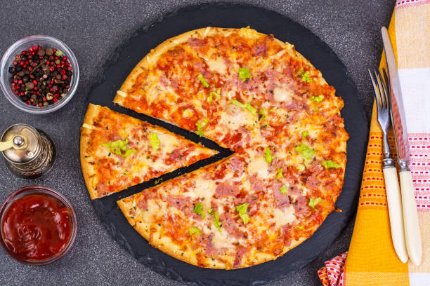 istock Pizza with ham and cheese on black stone 672582216