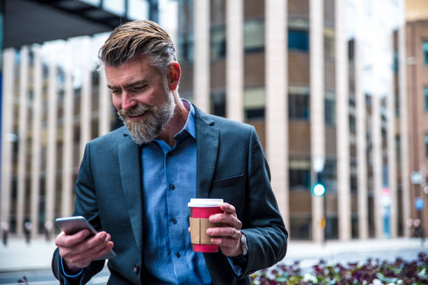 istock Man with a coffee cup texting on the street 672590570