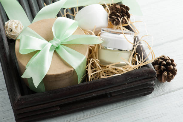 Beauty products, gift with green ribbon and pine cones composition on shabby white wooden table. Top view