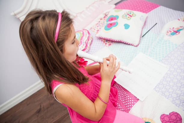 istock Little girl playing flute 672593446