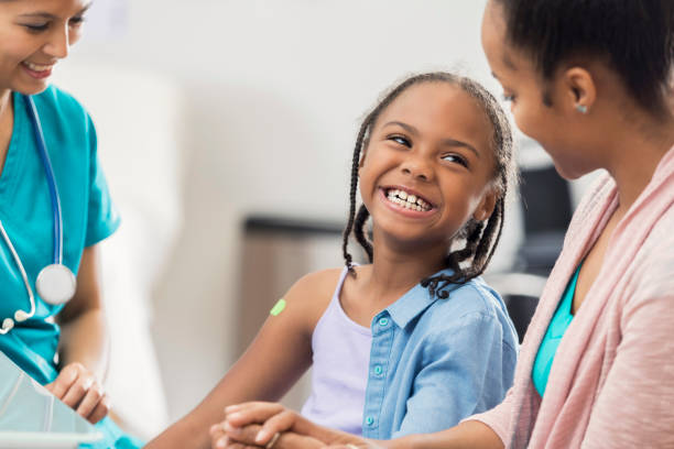 istock Smiling girl receives immunization from nurse 672596872