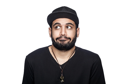 Portrait of young thoughtful confused man with black t-shirt and cap thinking. studio shot, isolated on white background.