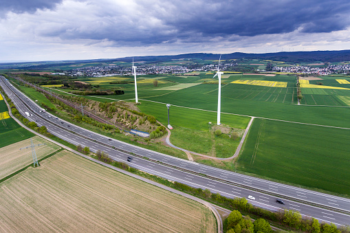 German landscape - cloudscape and Taunus mountains, aerial view. Highway, railroad track and wind turbines.