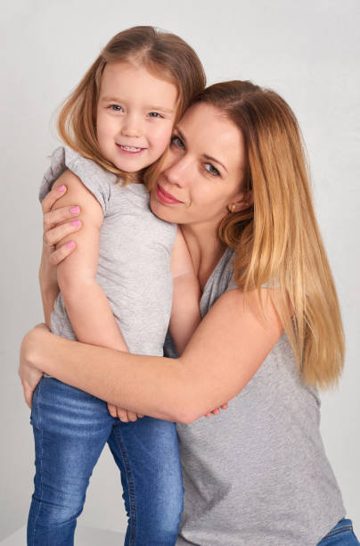 istock Mom and daughter in jeans on a gray background 672600700