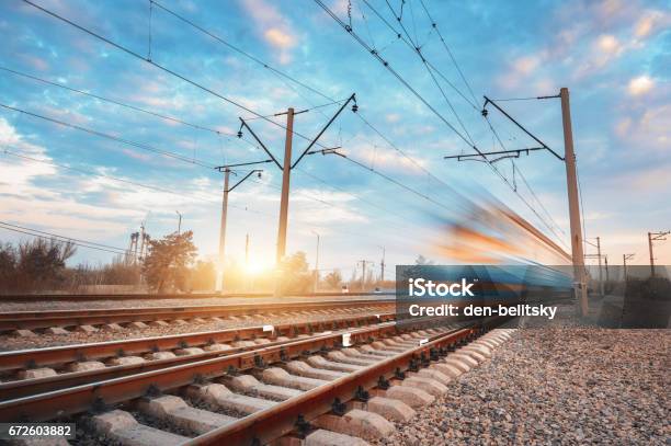 High Speed Blue Passenger Train In Motion On Railroad At Sunset Blurred Commuter Train Railway Station Against Colorful Sky Railroad Travel Railway Tourism Rural Industrial Landscape Vintage Stock Photo - Download Image Now
