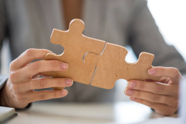 istock Close up on hands putting together puzzle pieces 672609216