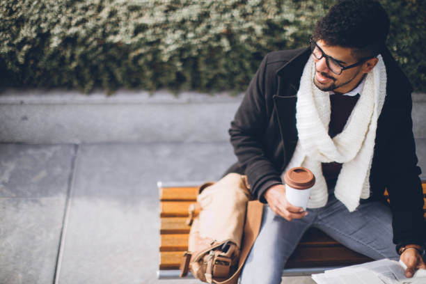 Successful young african man reading a newspaper while drinking coffee