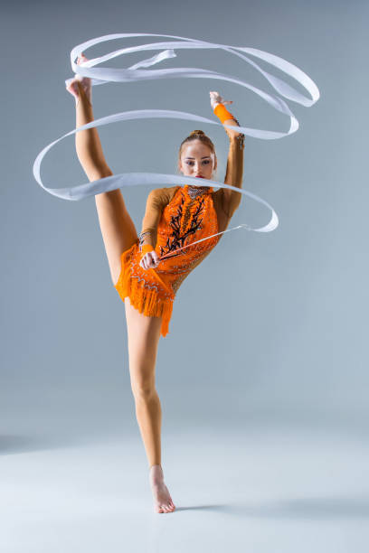 istock teenager doing gymnastics dance with white ribbon on a blue back 672617828