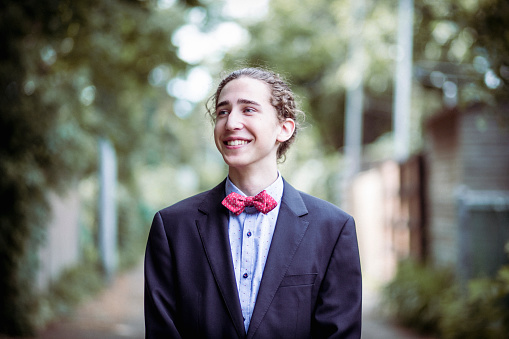 Portrait of a teenager smiling and wearing a suit for his prom night