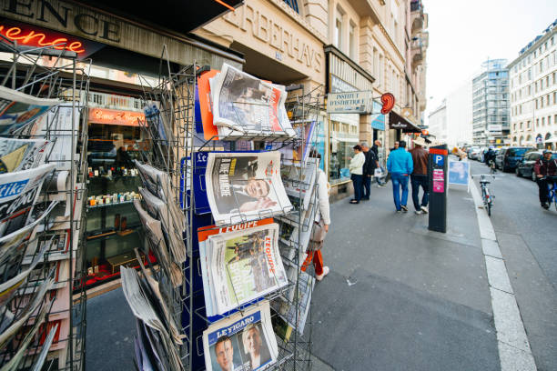 buying international press with Emmanuel Macron and Marine le Pen Paris: International newspapers at press kiosk wih newspaper and pictures of French Presidential election candidates, Emmanuel Macron, Marine Le Pen a day after first round of French Presidential election on April 23, 2017 newspaper seller stock pictures, royalty-free photos & images