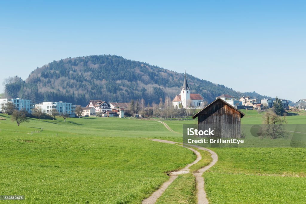 Country landscape, dirt road in front of swiss village Alley Stock Photo