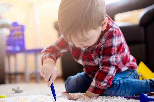 istock Cute little boy sitting on the floor and drawing 672651360