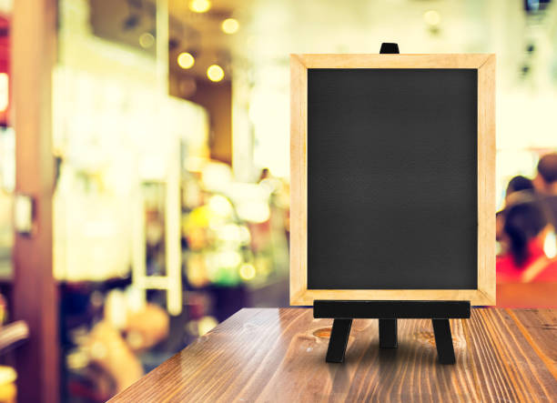 istock Blackboard with easel on wood table at blurred coffee shop background,Mock up for display or montage of design for online shopping promotion 672689710