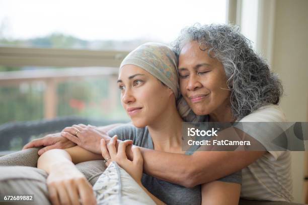 Hawaiian Woman In 50s Embracing Her Mid20s Daughter On Couch Who Is Fighting Cancer Stock Photo - Download Image Now