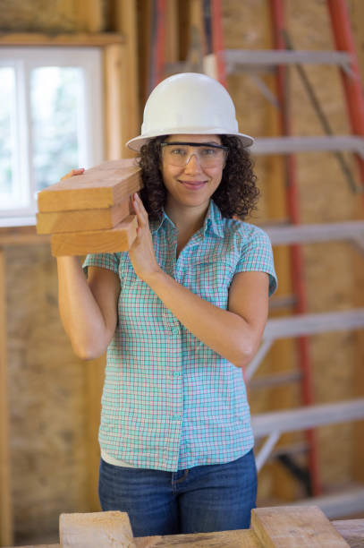 istock Female construction worker carries a stack of 2x6 lumber for an interior remodel 672690228