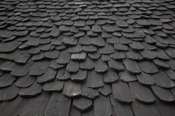 Photo of Perspective natural Black painted house wooden tiles roof random pattern background.