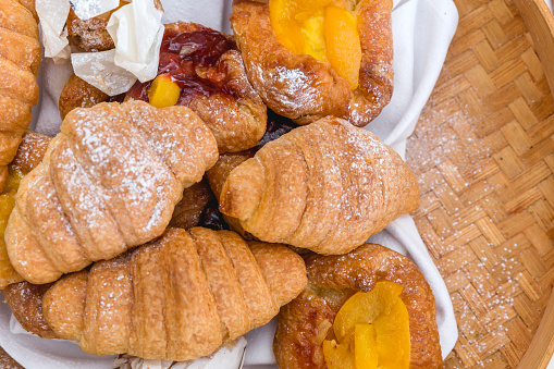 Collection of croissants stack together above white napkin.